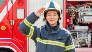 消防車と共に敬礼する笑顔の消防士