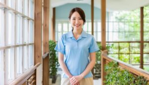 室内で立ち笑顔を見せる介護士の女性