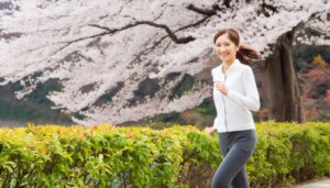 桜の下でジョギングを楽しむ笑顔の女性