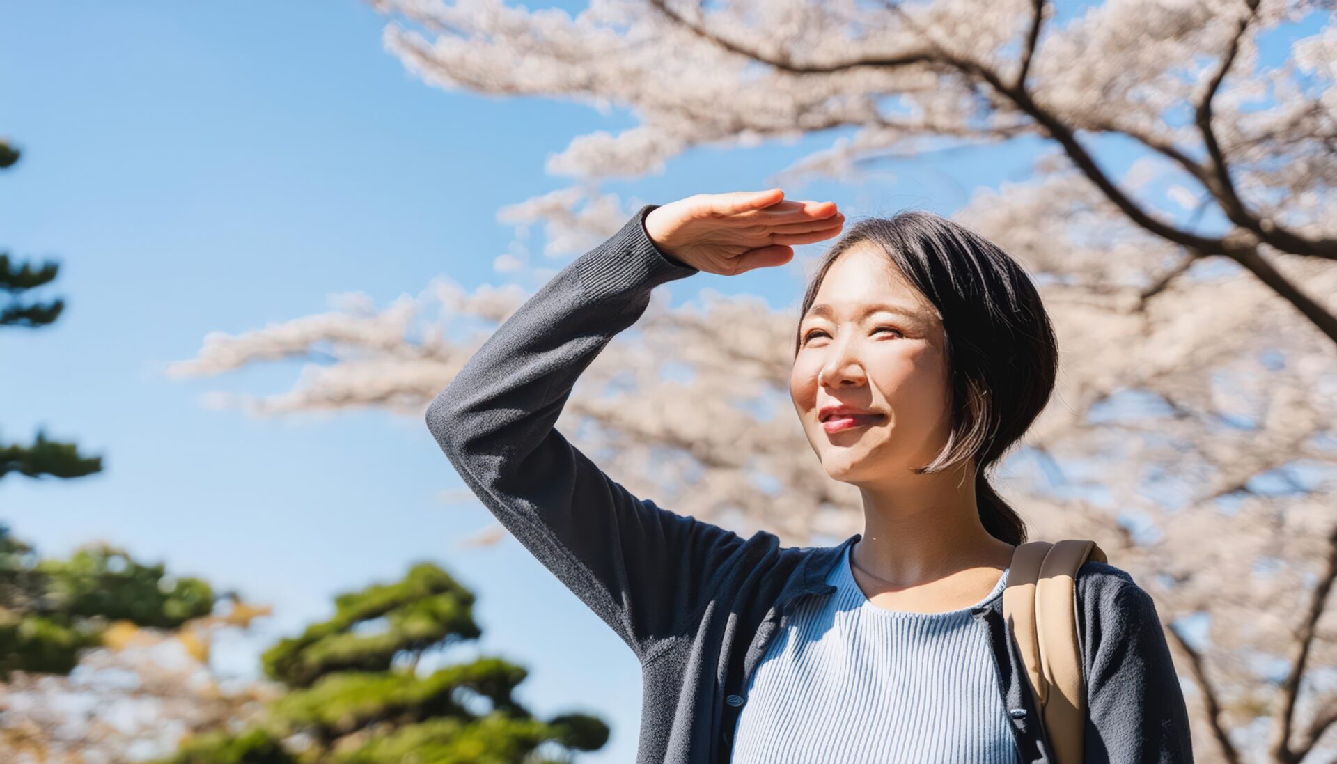 桜の木の下で空を見上げる女性