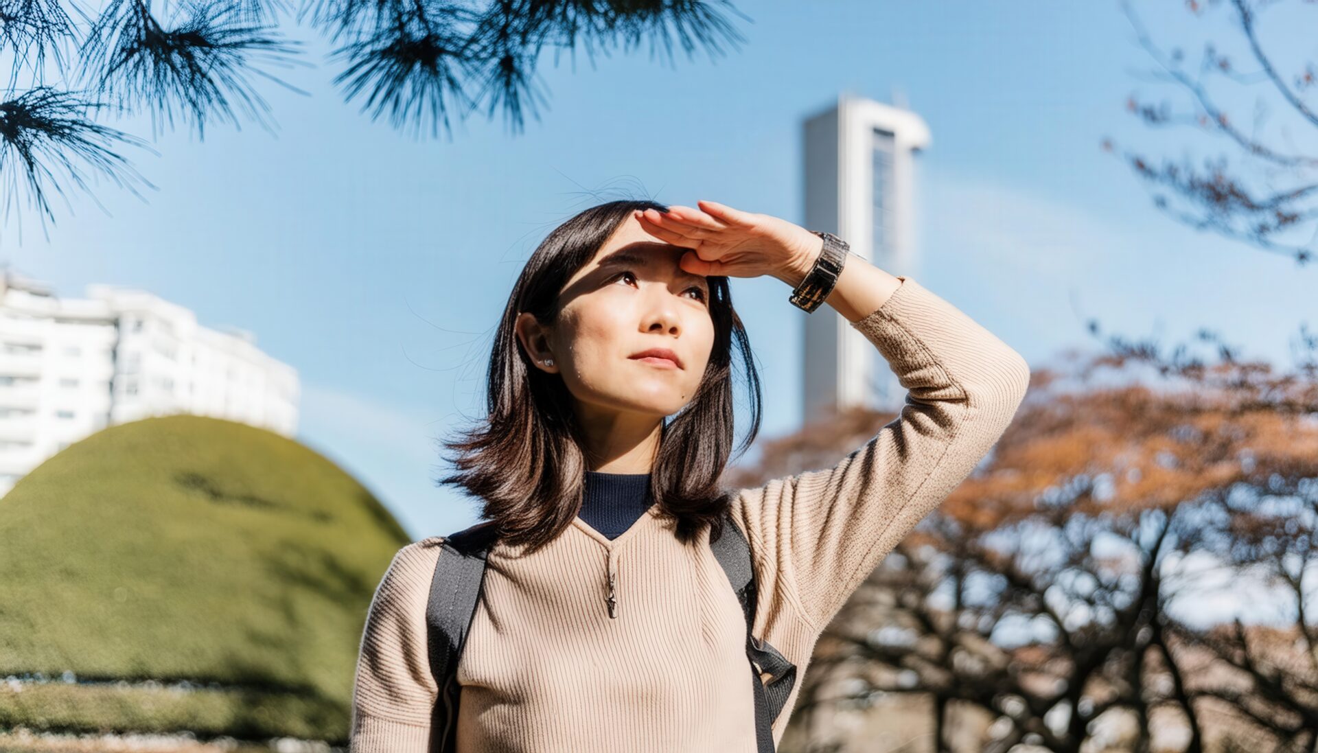 都会の空の下で遠くを見つめる女性