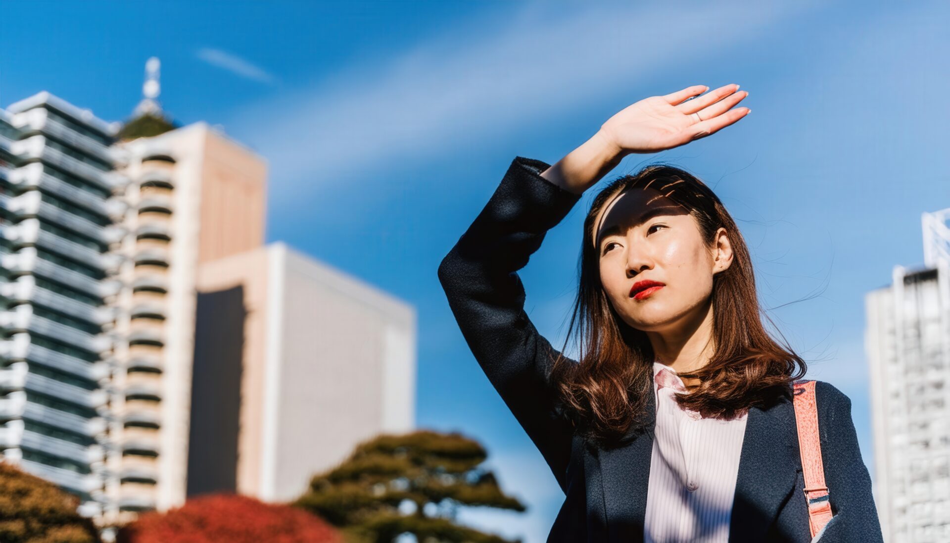 都会で日差しを遮るスーツ姿の女性