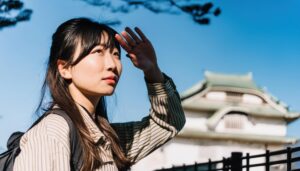 日本の城を背景に空を見上げる女性