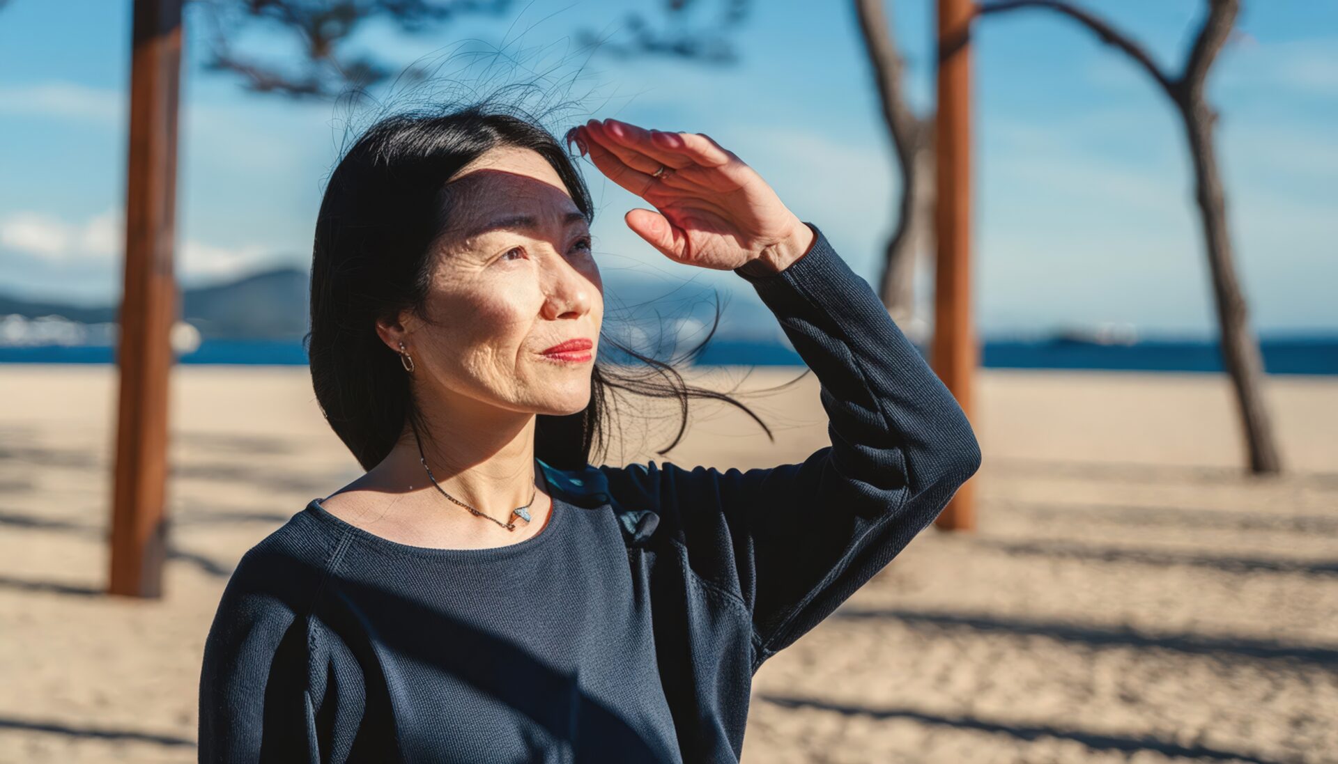 砂浜で風を感じながら遠くを見る女性