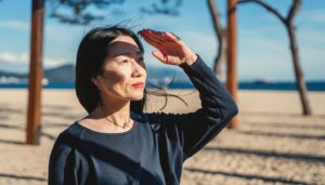 砂浜で風を感じながら遠くを見る女性