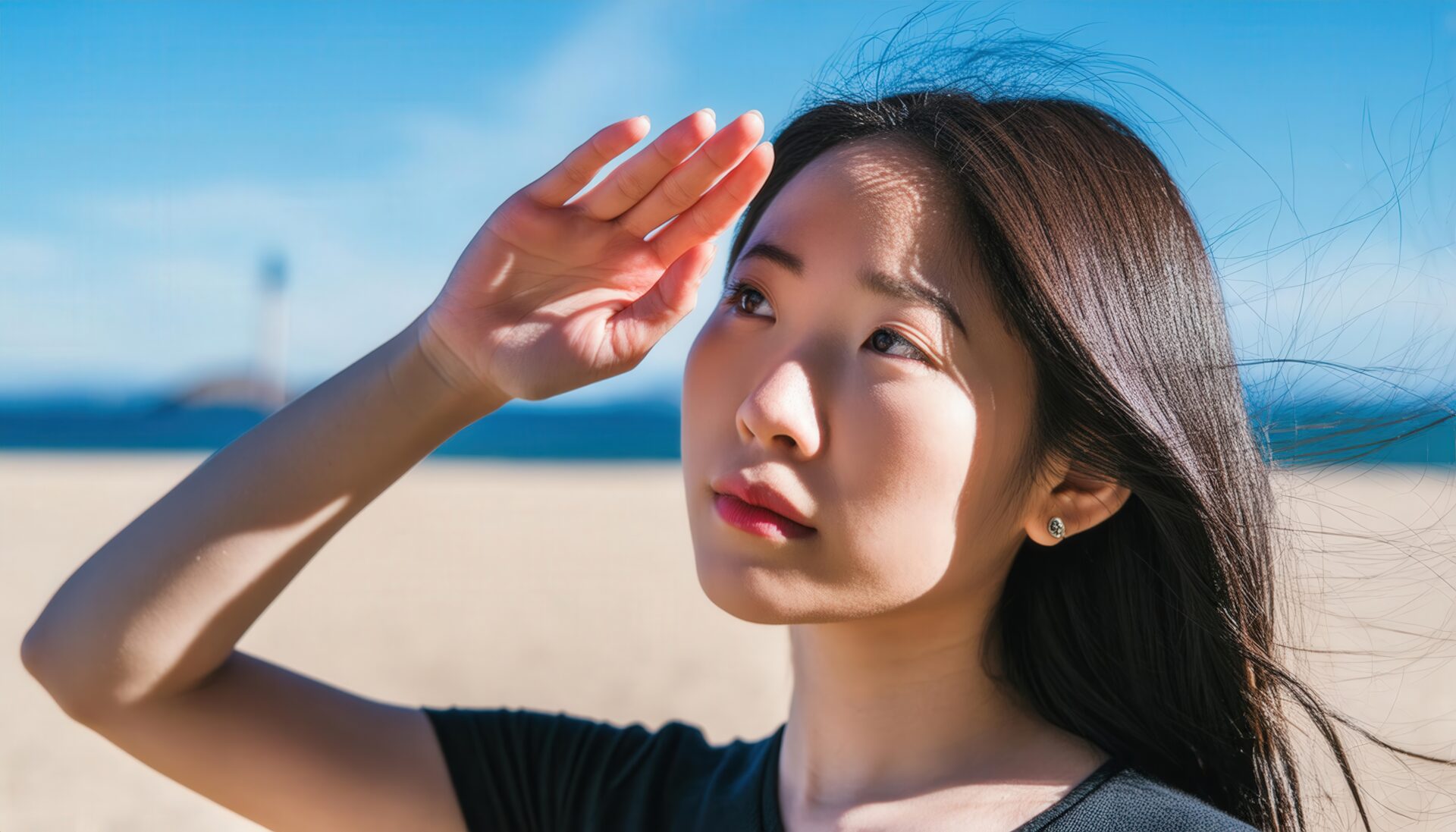 青空と海を背景に見上げる女性