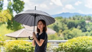 黒い日傘を持つ女性が屋外で微笑む