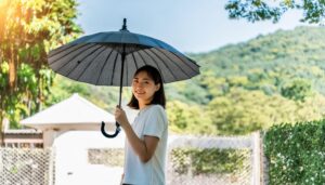 白い日傘を持つ女性が木々の中で微笑む