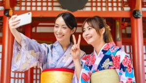 神社でピースサインをする着物姿の2人組