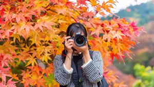 カメラを構える紅葉を背景にした女性
