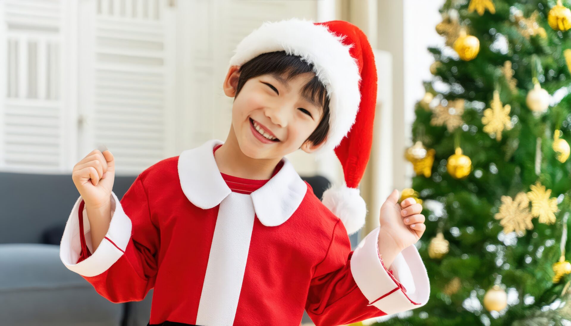 サンタクロース衣装を着た笑顔の子供（クリスマスツリー）