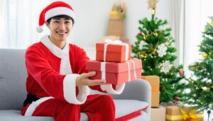 笑顔の男性がクリスマスツリー前でプレゼントを渡す