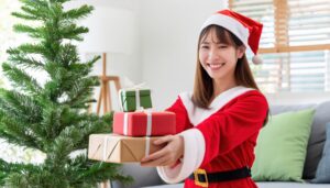 サンタ衣装を着た女性がプレゼントを渡す（クリスマスツリー）