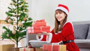 サンタクロースの衣装で赤いリボンのプレゼントを持つ女性