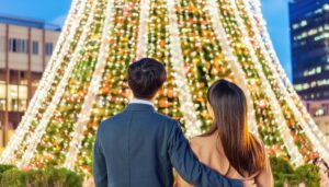 夜景の中、大きなクリスマスツリーを見るカップル