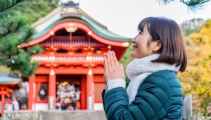 神社の前で手を合わせる女性