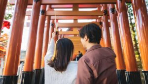 神社の赤い鳥居を歩くカップル