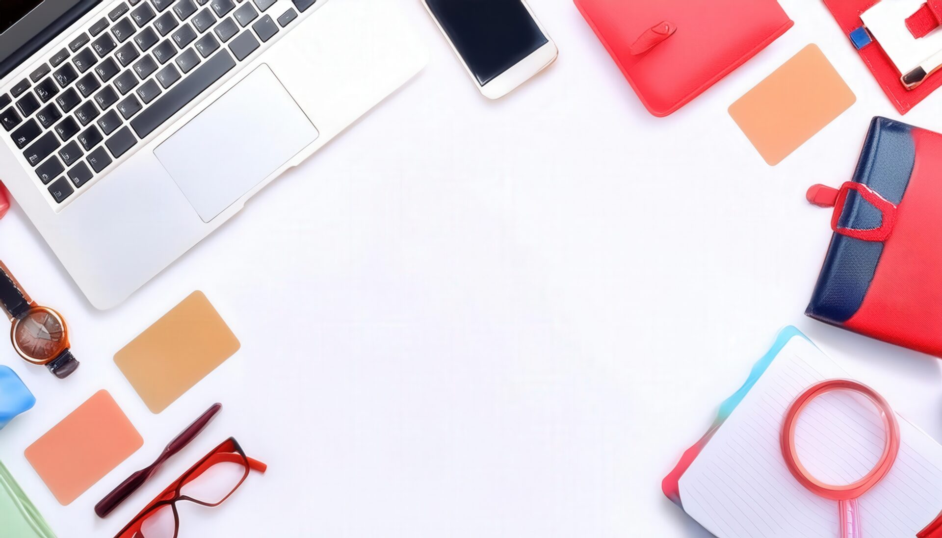 ノートパソコンとデスク小物が並ぶ白い背景のフラットレイ