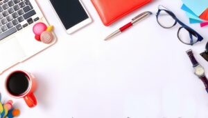 ノートパソコンと時計が並ぶ白い背景のフラットレイ