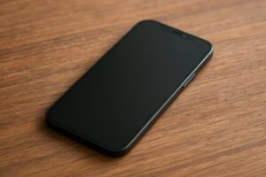 木目の上に置かれたスマートフォン（黒画面）