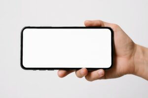 横向きに持たれたスマートフォン（白背景）