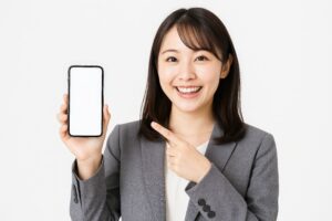 スーツ姿の女性がスマホを紹介（白背景・笑顔）