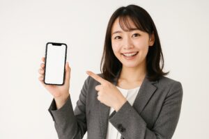 グレースーツの女性がスマホを紹介（白背景・笑顔）