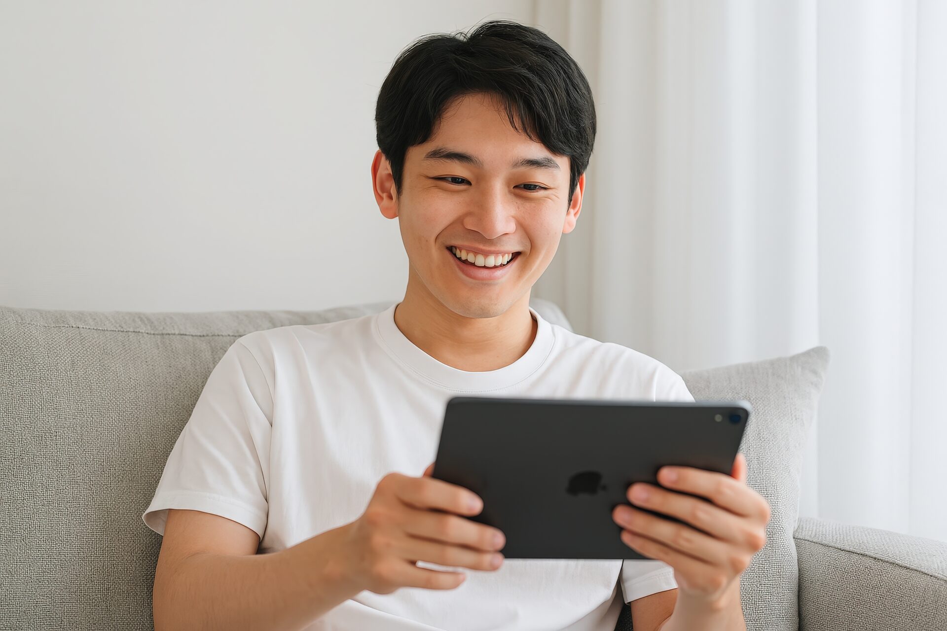 タブレットをソファで操作する若い男性