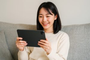 ソファでくつろぎながらタブレットを見る女性