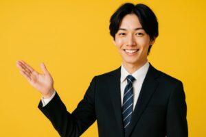 黄色背景で片手を上げて紹介するスーツ姿の若い男性