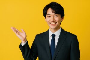 スーツ姿で左手を広げて案内する若い男性