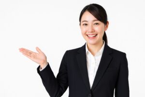 スーツ姿で笑顔の女性が左手を上げて案内している様子