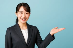 水色背景でスーツ姿の女性が右手を広げて案内する様子
