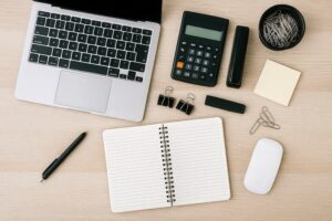 木目調デスクに並ぶノートパソコンと文房具