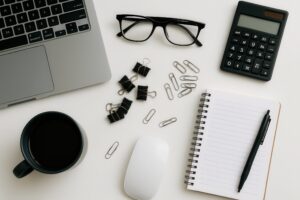 白いデスクに並ぶコーヒーと文房具