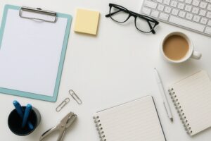 白いデスクに置かれたクリップボードとノート