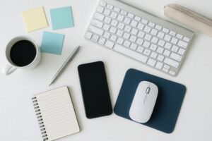 白いデスクに並ぶキーボードと文房具