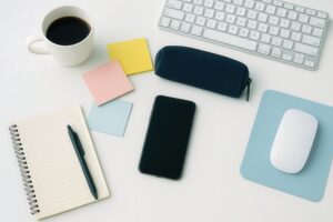 白いデスクに並ぶノートとビジネスツール