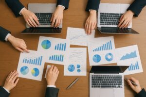 会議テーブルに広がるグラフ資料とノートパソコン