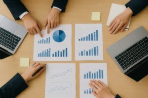 ビジネス会議で分析グラフを指差す手とノートパソコン