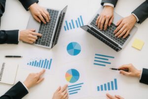 ノートパソコンと棒グラフが並ぶ会議のテーブル