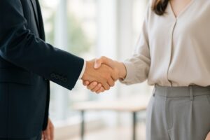 オフィスカジュアルの女性と握手するビジネスマン
