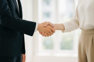 シンプルな服装の女性と握手するビジネスマン