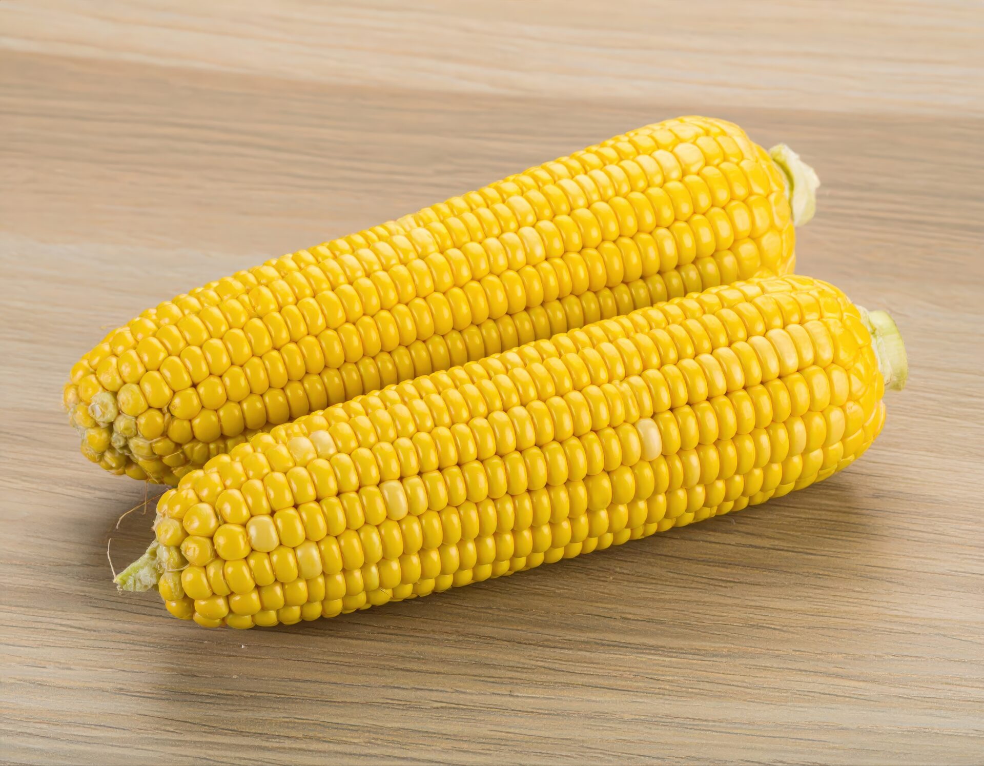 皮をむいた2本のトウモロコシを木製テーブルの上に置いた