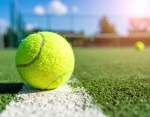 白線際に置かれたテニスボールと青空