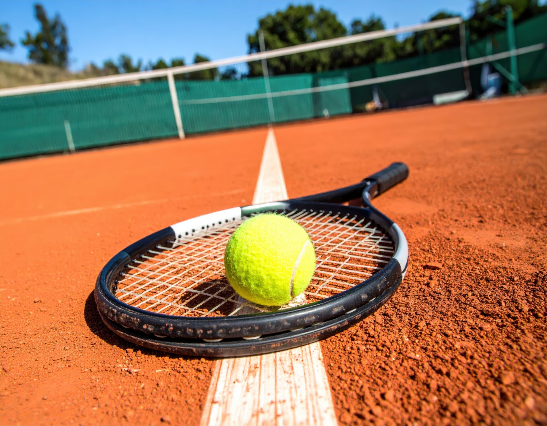 クレイコートに置かれたラケットとテニスボール