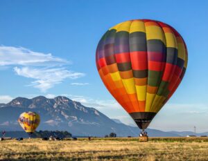 山を背景に浮かぶカラフルな熱気球