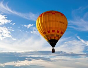 青空に浮かぶ黄色とオレンジの熱気球