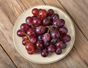 白い皿に盛られた赤いブドウ