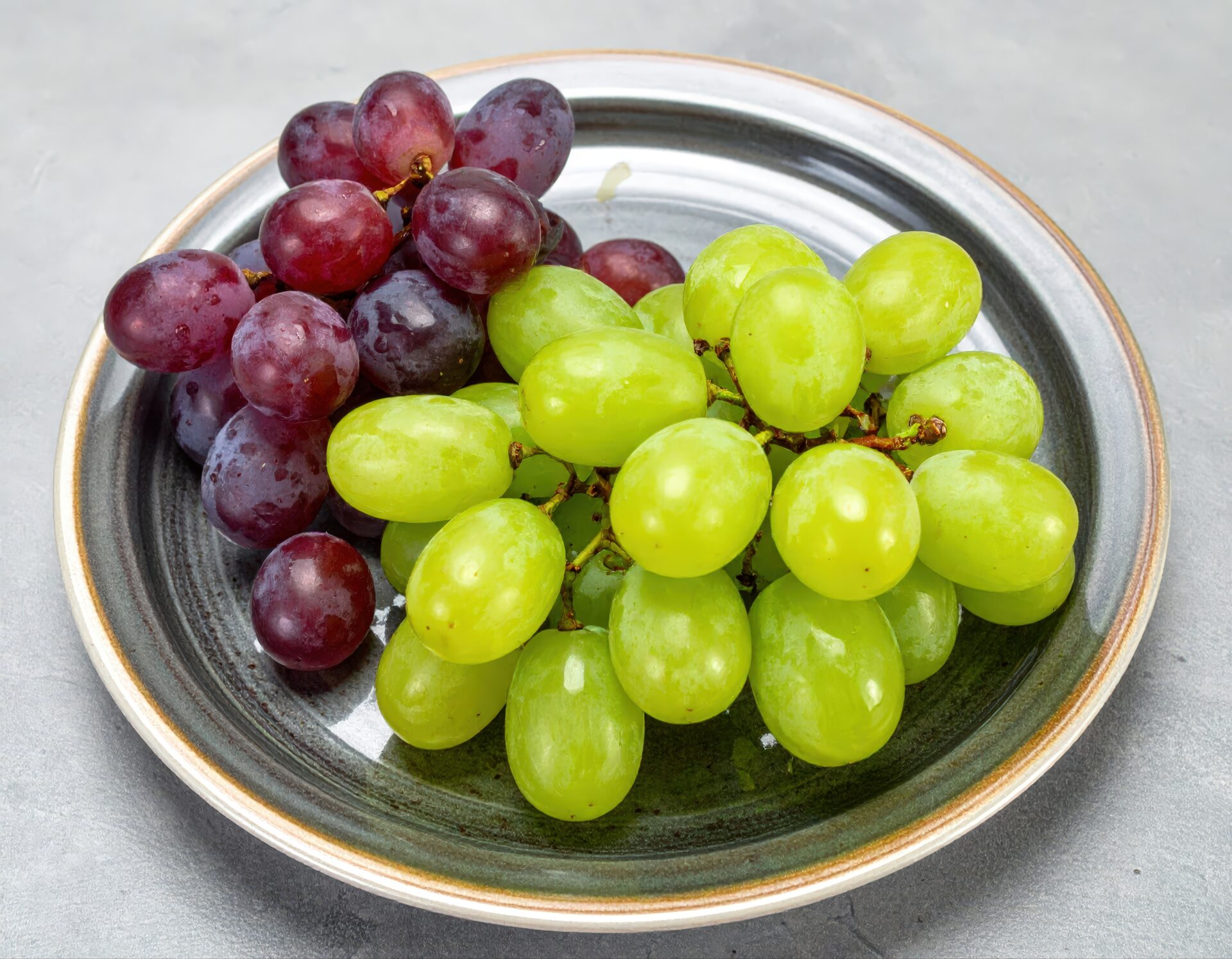 灰色の皿に盛られた赤と緑のブドウ